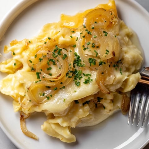 Zarte hausgemachte Käse-Spätzle, geschichtet mit geschmolzenem Käse und karamellisierten Zwiebeln.
